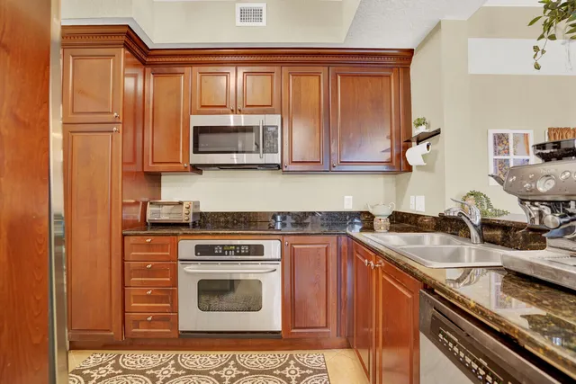 a kitchen with granite countertop a sink stove and microwave