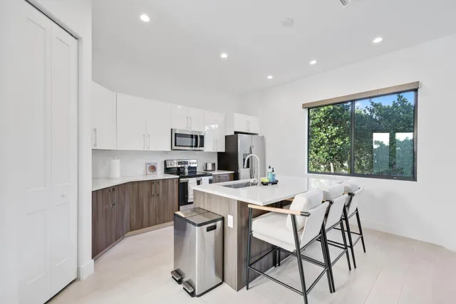 a kitchen with stainless steel appliances a dining table chairs and a refrigerator