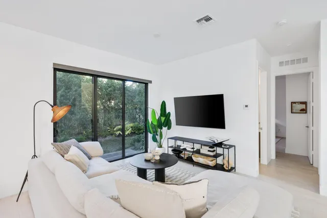 a living room with furniture a flat screen tv and a floor to ceiling window