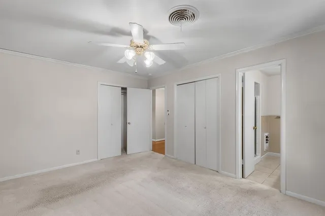 an empty room with a chandelier fan and closet area