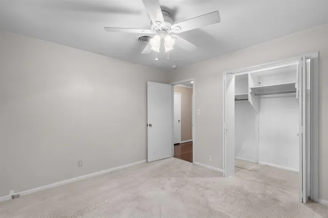 an empty room with chandelier fan and closet