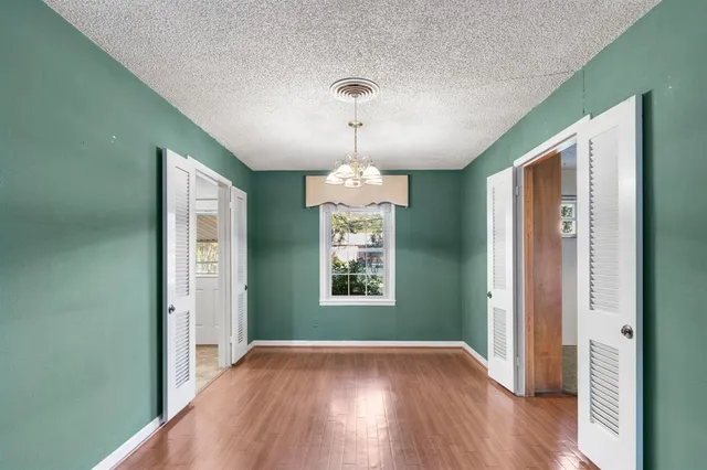 a view of a room with wooden floor chandelier and windows