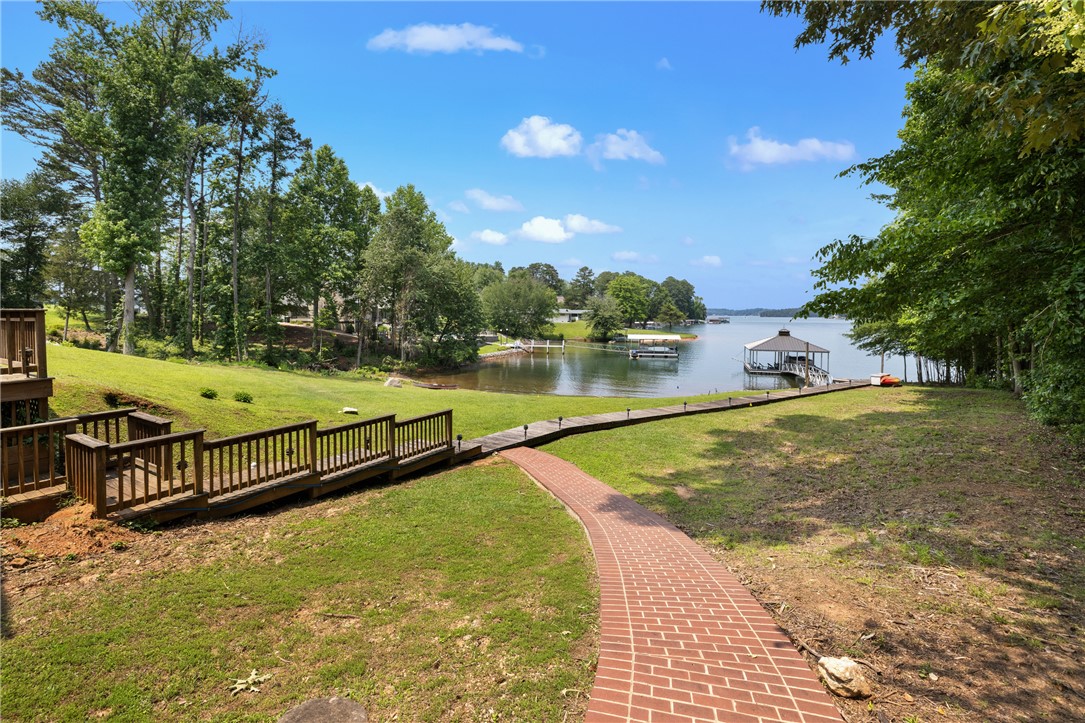 408 Northampton Road Seneca, SC 29672 - Photo 45 of 49 The outdoor living experience is just as impressive: a brick path leads to a lakeside boardwalk with landscape lighting and outdoor shower, guiding you to a private double-slip covered dock with power, water, and boat lifts. An exterior-access full bath adds convenience for long lake days, while the gently sloping grassy yard offers room for a future beach area along the shoreline or continued recreation.