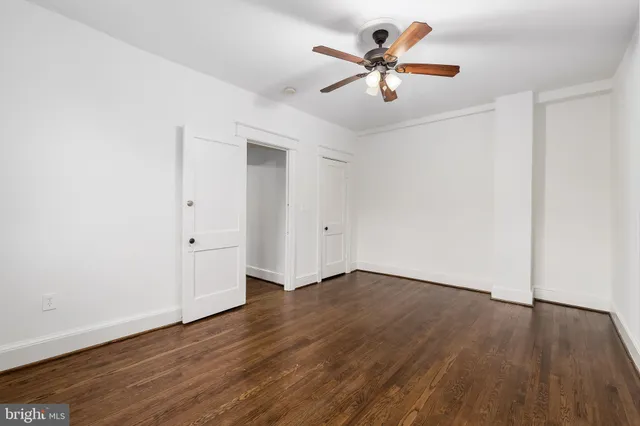 an empty room with wooden floor a ceiling fan and windows