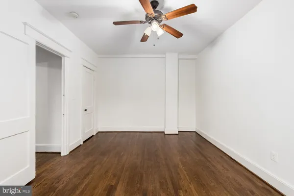 an empty room with wooden floor and ceiling fan