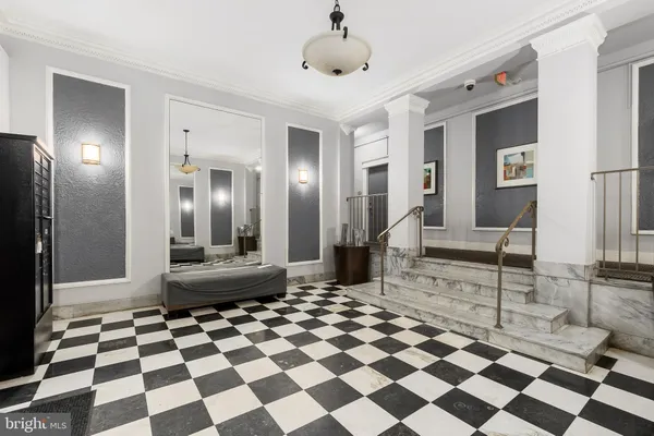 a living room with a black white checkered floor with a gaming machine and a rug