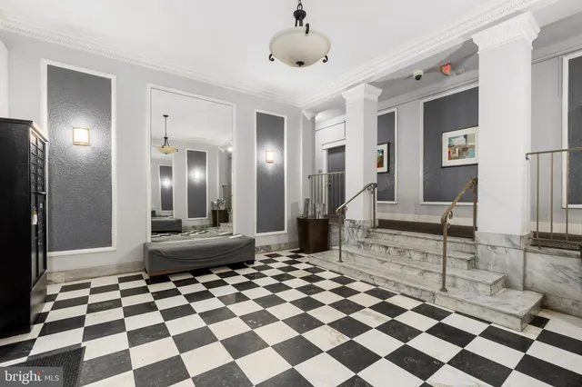 a living room with a black white checkered floor with a gaming machine and a rug