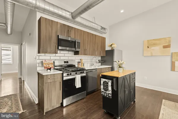 a kitchen with stainless steel appliances granite countertop a stove top oven a sink dishwasher and a refrigerator with wooden floor