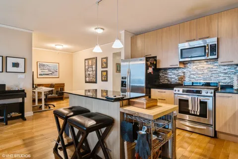 a kitchen with granite countertop a stove a sink a dining table and chairs