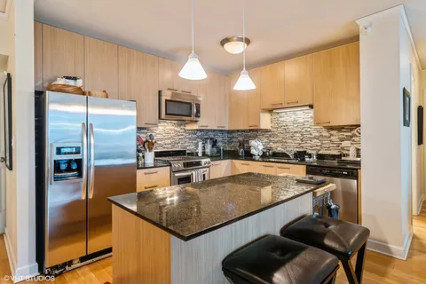 a kitchen with stainless steel appliances granite countertop a sink a stove and refrigerator