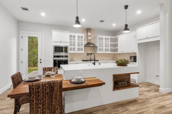 a kitchen with stainless steel appliances granite countertop a sink a stove a refrigerator cabinets and chairs