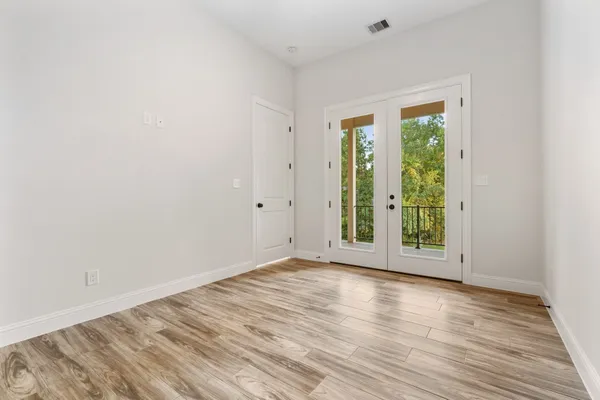 a view of an empty room with wooden floor and a window