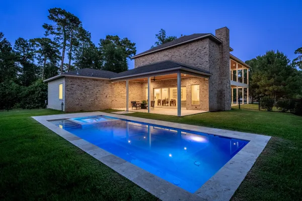 a view of pool with lawn chairs and plants