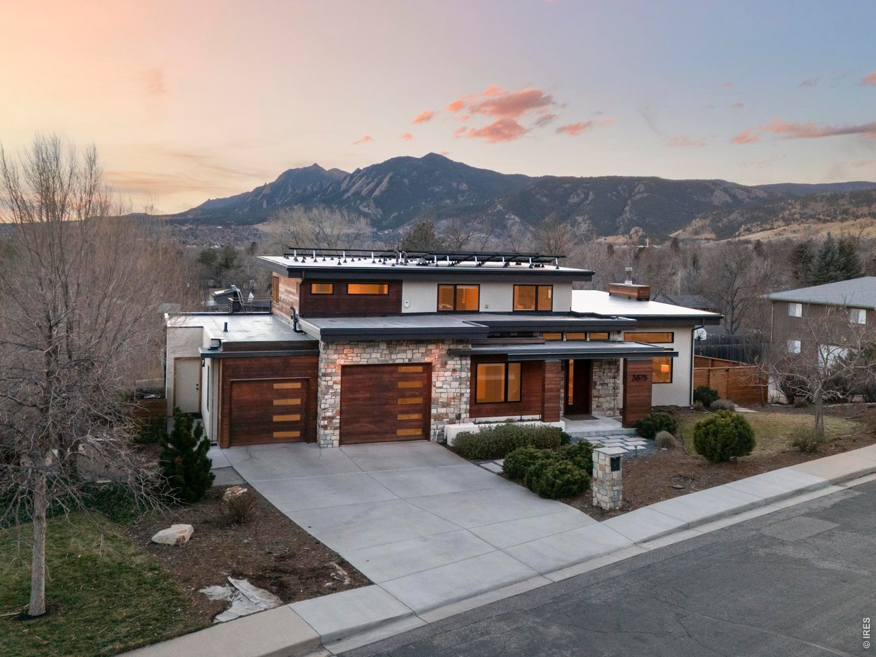 a front view of a house with a yard and mountain view in back