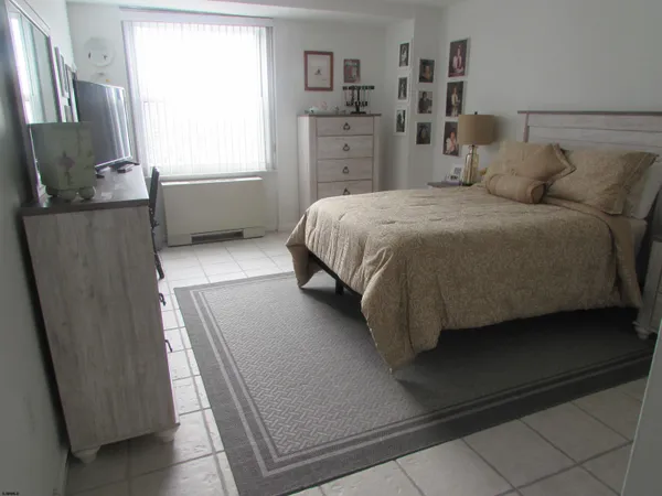a bedroom with a bed and a flat tv screen on dresser