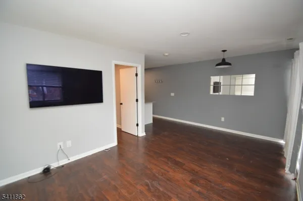 a view of an empty room with wooden floor and closet