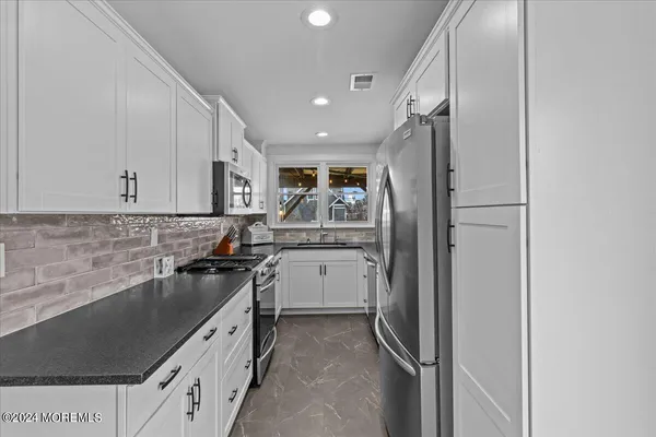 a kitchen with stainless steel appliances granite countertop a sink a stove and cabinets