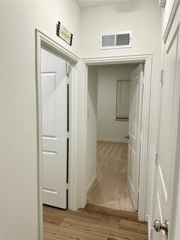 a view of a hallway with wooden floor and closet