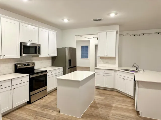 a kitchen with a sink stove top oven and refrigerator