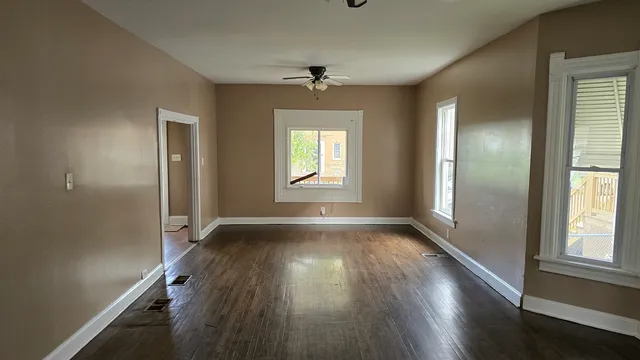 an empty room with wooden floor and windows