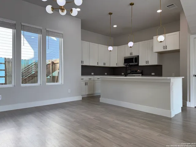 a kitchen with stainless steel appliances a sink a stove a microwave a center island and cabinets