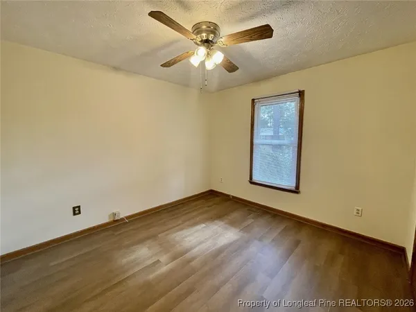 an empty room with a chandelier fan and windows