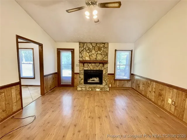a view of an empty room with wooden floor fireplace and a window