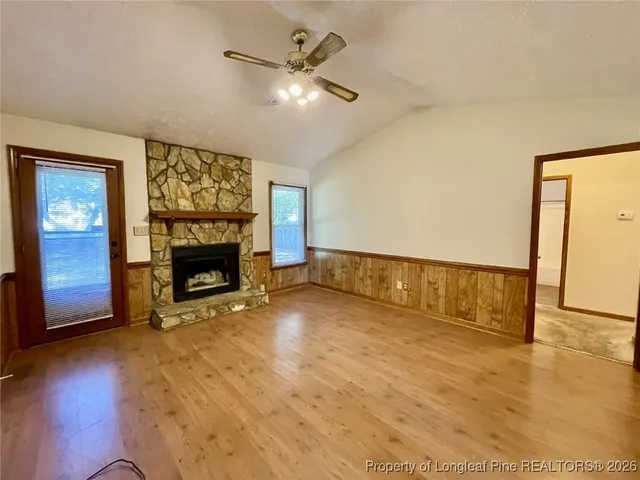 an empty room with windows fireplace and wooden floor