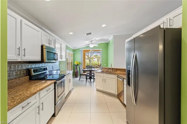 a kitchen with stainless steel appliances granite countertop a refrigerator oven a sink dishwasher a dining table and chairs with wooden floor