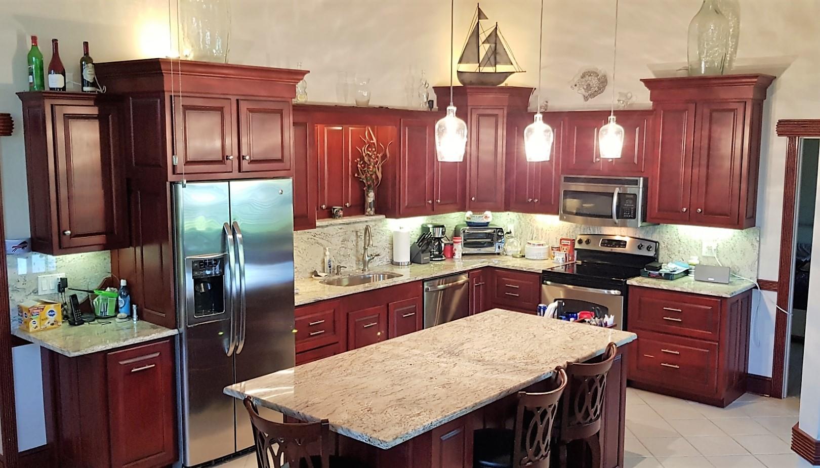 a kitchen with granite countertop stainless steel appliances a table chairs microwave and refrigerator