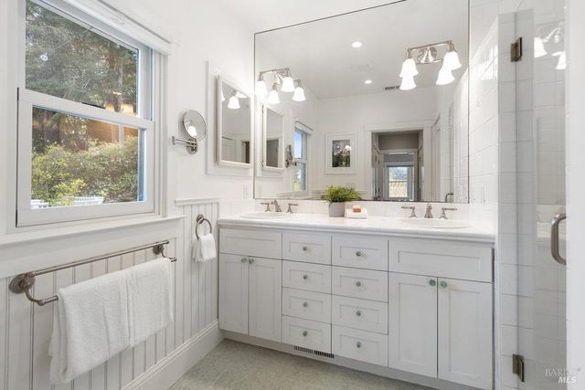 a bathroom with a double vanity sink mirror and next to a window
