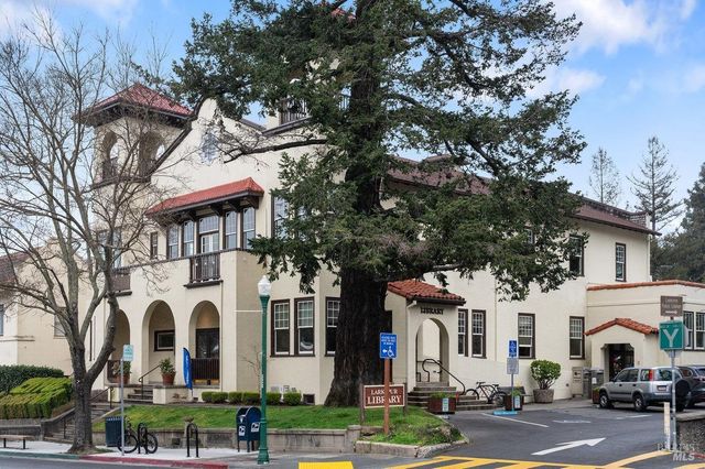 a view of a white house with large trees