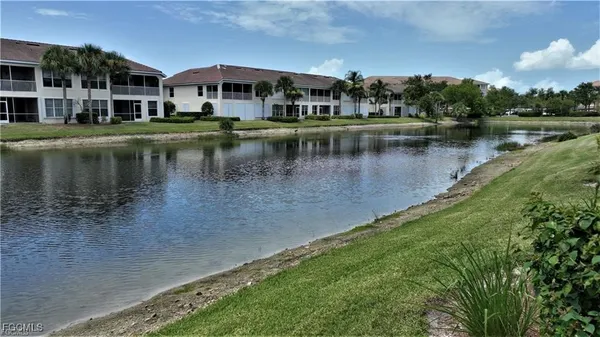 a view of a lake with a yard and large trees