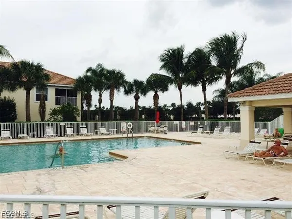 a view of a swimming pool with a lounge chair and palm trees