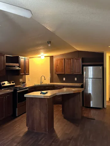 a kitchen with stainless steel appliances granite countertop a sink a stove a refrigerator a microwave oven with wooden floor and cabinets