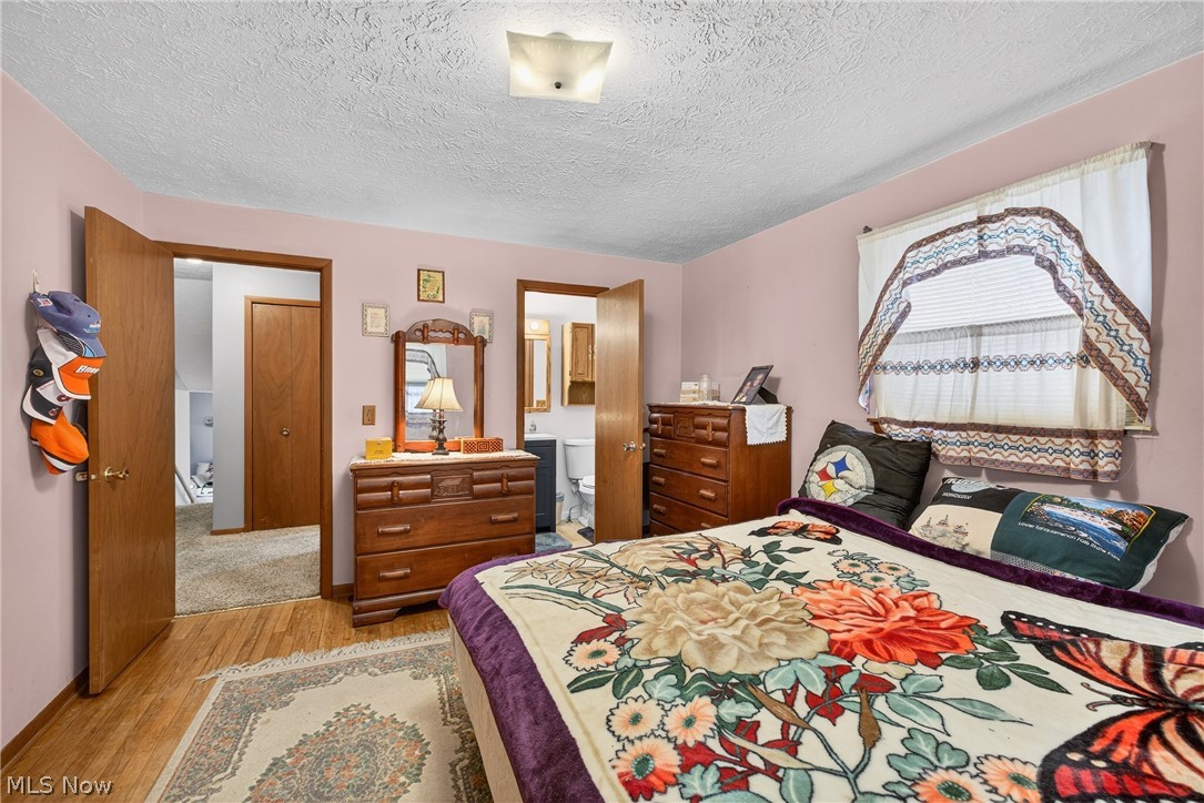 4404 Florida Street Perry, OH 44081 - Photo 12 of 24 Bedroom featuring light wood-style flooring, connected bathroom, and a textured ceiling