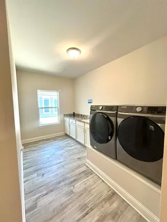 a view of kitchen and empty room with wooden floor