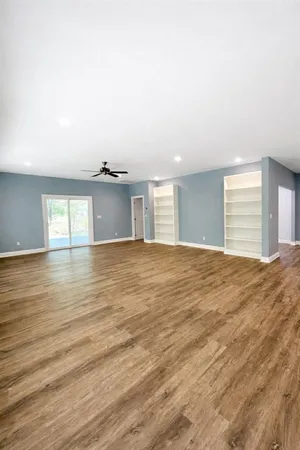 a view of an empty room with window and wooden floor