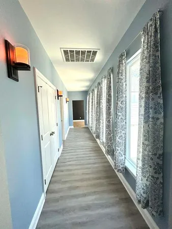 a view of a hallway with wooden floor and windows