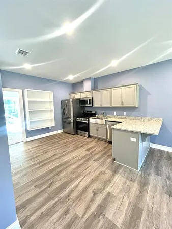 a large kitchen with stainless steel appliances kitchen island granite countertop a stove a sink a refrigerator and white cabinets