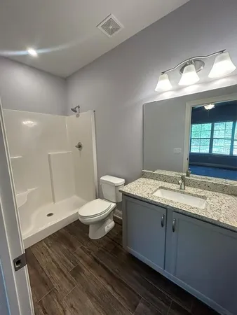 a bathroom with a granite countertop sink toilet a large mirror a vanity and shower