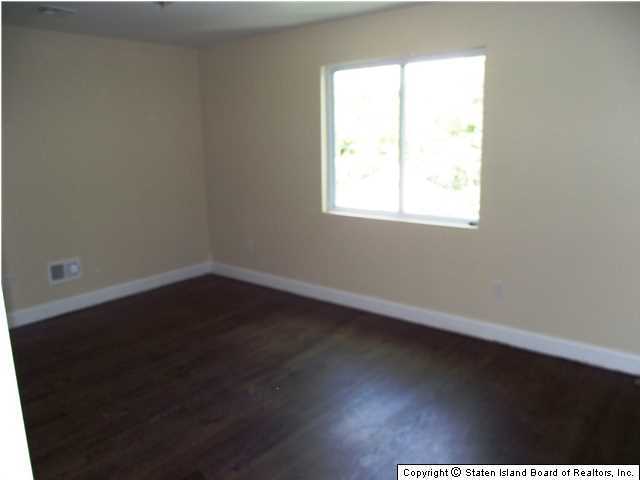 29 Midland Road Staten Island, NY 10308 - Photo 12 of 20 an empty room with wooden floor and windows