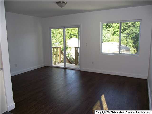 29 Midland Road Staten Island, NY 10308 - Photo 7 of 20 an empty room with wooden floor and windows