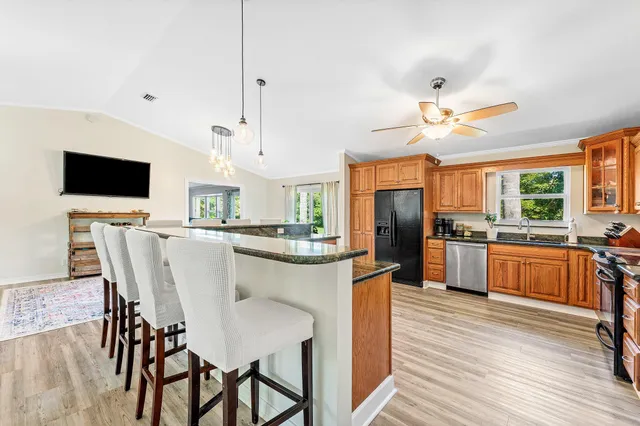 a kitchen with stainless steel appliances kitchen island granite countertop a table chairs and a refrigerator