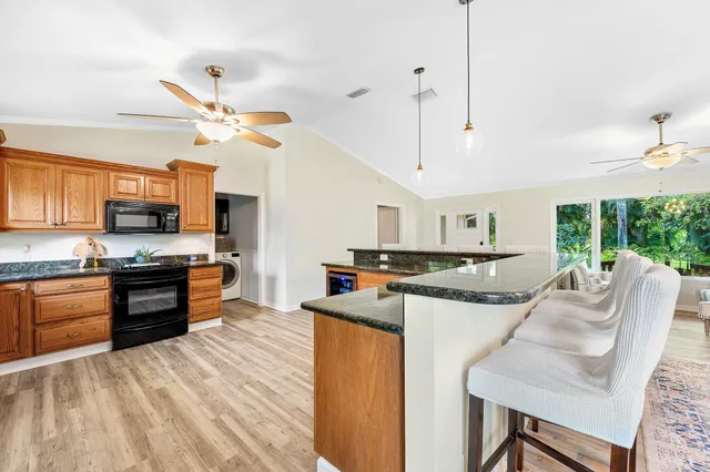 a kitchen with stainless steel appliances kitchen island granite countertop a table chairs and a refrigerator