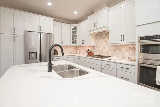 a kitchen with granite countertop a sink stainless steel appliances and white cabinets