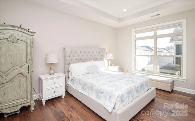 a bedroom with a large bed and wooden floor