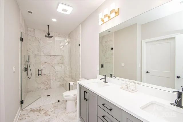 a bathroom with a sink double vanity granite toilet and shower