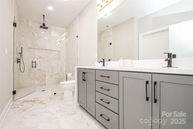 a spacious bathroom with a double vanity sink toilet mirror and shower