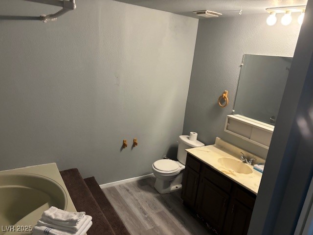 4640 Koval Lane, Unit 49A Las Vegas, NV 89109 - Photo 11 of 17 Bathroom with wood finished floors, toilet, vanity, and a tub to relax in